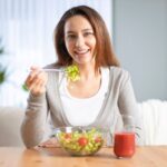 dieta low fodmap: mulher sorridente comendo salada