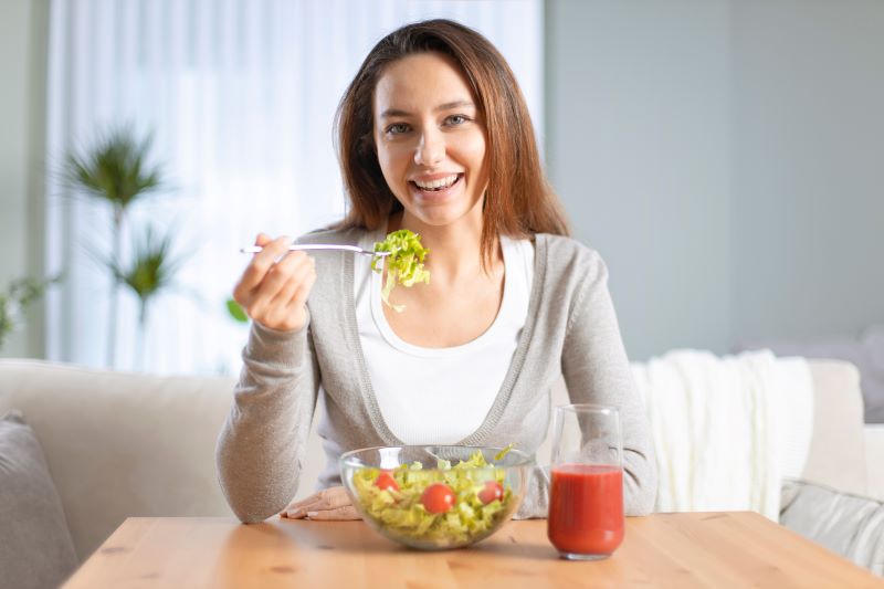 dieta low fodmap: mulher sorridente comendo salada